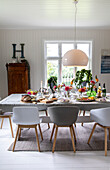 Festively laid dining table with floral decorations and white shell chairs