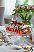 Sponge roll with chocolate icing and strawberries on a glass plate