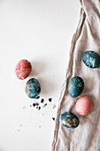 Colourfully painted Easter eggs, on a white surface, beige tablecloth