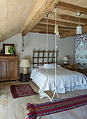 Bedroom with wooden swing, oriental carpets and rustic wooden furniture
