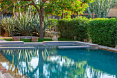 Swimmingpool mit Agaven und Oleanderhecke in marokkanischem Garten