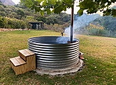 Metal hot tub with wooden steps in the garden