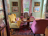 Round wooden table with yellow sofa and pink armchairs in an elegant living room