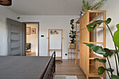 Bedroom with wooden floor, plants and open wardrobe made of bamboo