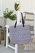 Self-sewn bag made from rag rug hangs on white chair