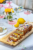 Poppy seed cake with lemon icing and edible flowers on a wooden board