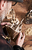 Man looking at a hand-carved wooden miniature of a city