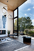 Modern living area with large window front, abstract wall art and geometric hanging lamp