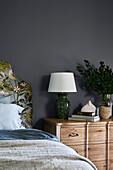 Wooden bed with floral headboard next to rustic bedside table