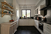 Bright country-style kitchen with black tiles and open wooden shelving
