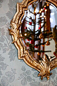 Decorated mirror with gold-coloured frame and reflected Christmas tree