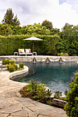 Natural pool with stone edge and sun loungers