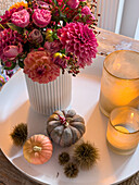 Autumn bouquet of dahlias with candles and decorative pumpkins on a white coffee table