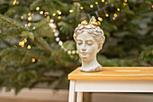 Bust of Aphrodite with mini Christmas baubles in front of a blurred Christmas tree