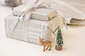 Gifts wrapped in newspaper with a deer figure and mini Christmas tree