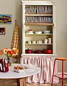 Open kitchen cupboard with crockery and red cooking pots