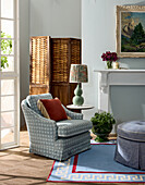 Patterned upholstered armchair in the living room with rattan screen