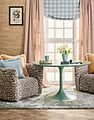 Round, mint-coloured table between patterned armchairs in the living room