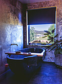 Free-standing bathtub in modern bathroom with large window view