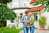 Young couple is looking at documents in front of a house, Hamburg, Germany