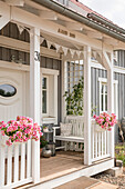 Veranda von selbstgebauten Eigenheim mit weißer Bank und Blumenkörben im Sonnenlicht, Korbach, Hessen, Deutschland, Europa
