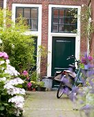 A bicycle in front of a green-painted, English-style door in an inner courtyard with plants