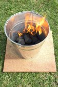 Barbecue bucket with burning charcoal