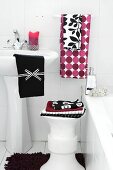 Verschiedene Handtücher neben der Badewanne auf Hocker und Waschbecken
