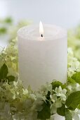 Candle in wreath of hydrangea flowers and mint