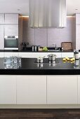 Detail of a designer kitchen with stainless steel extractor hood above kitchen island