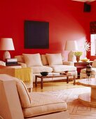 Dark blue painting above pale sofa set on bright red wall
