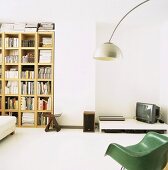 Medienecke auf niedrigem Tisch neben Bücherregal mit japanischem Hocker, 50er Jahre Designer-Sessel und Bogenlampe im Vordergrund