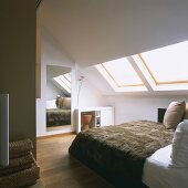 Schlafraum unter dem Dach mit großem Spiegel und Doppelbett mit Felldecke