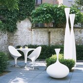 Courtyard with rustic garden wall, modern garden furniture and artworks