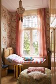 Traditionelles Schlafzimmer mit floraler Wandtapete, antikem Holzbett, Sitzpolster und Fellkissen