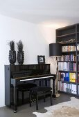Black glossy piano and bookcase in corner of room