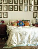 Doppelbett mit bunten Zierkissen und darüberhängender, großer Bildersammlung