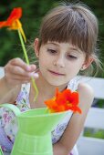 Mädchen stellt Kapuzinerkresseblüten in Krug