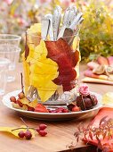 Glas mit Herbstlaub und Besteck als Tischdeko