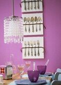 Laid table, display of cutlery on pink wall