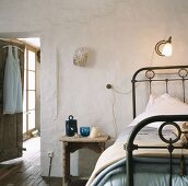 Altes Schlafzimmer mit Leselampe an der Wand befestigt und schmiedeeisernes Bettgestell