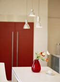 Tulpen in roter Vase und eine Kaffeetasse auf einem weißen Tisch
