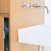 Nahaufnahme eines Waschbeckens vor Installationsschacht aus Holz mit Stauraum