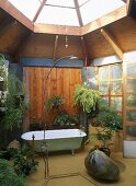 Freistehende Badewanne und offene Dusche unter verglaste Dachkuppel