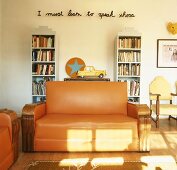 Wohnraum mit Sofas, Bücherregalen & Schriftzug an der Wand