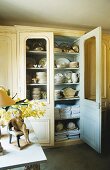 A cupboard with crockery and table linen