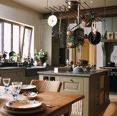 Rustikale Landhausküche mit Kochinsel unter hängenden Kochutensilien