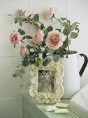Picture and roses in jug on edge of bathtub