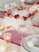 Gedeckter Tisch mit Rosen und Kerzen verziert
