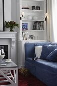 Wohnraumecke mit weißem Bücherschrank und blauer Couch